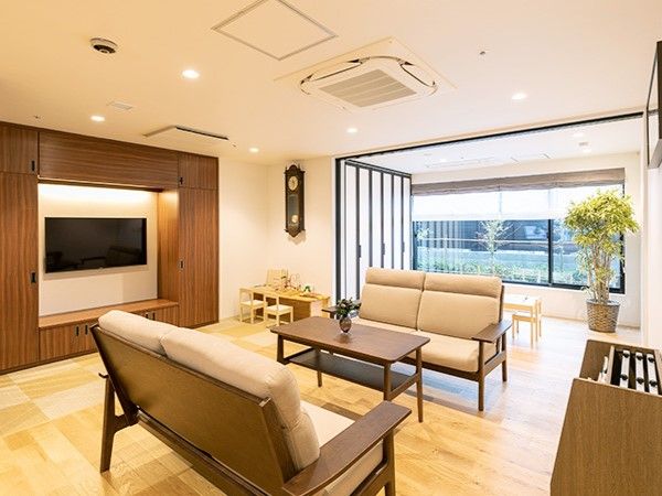 大型テレビが壁に設置され、二組のソファと一脚のテーブルがある広々とした空間