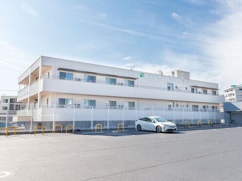前に白い車が停まっている白い建物