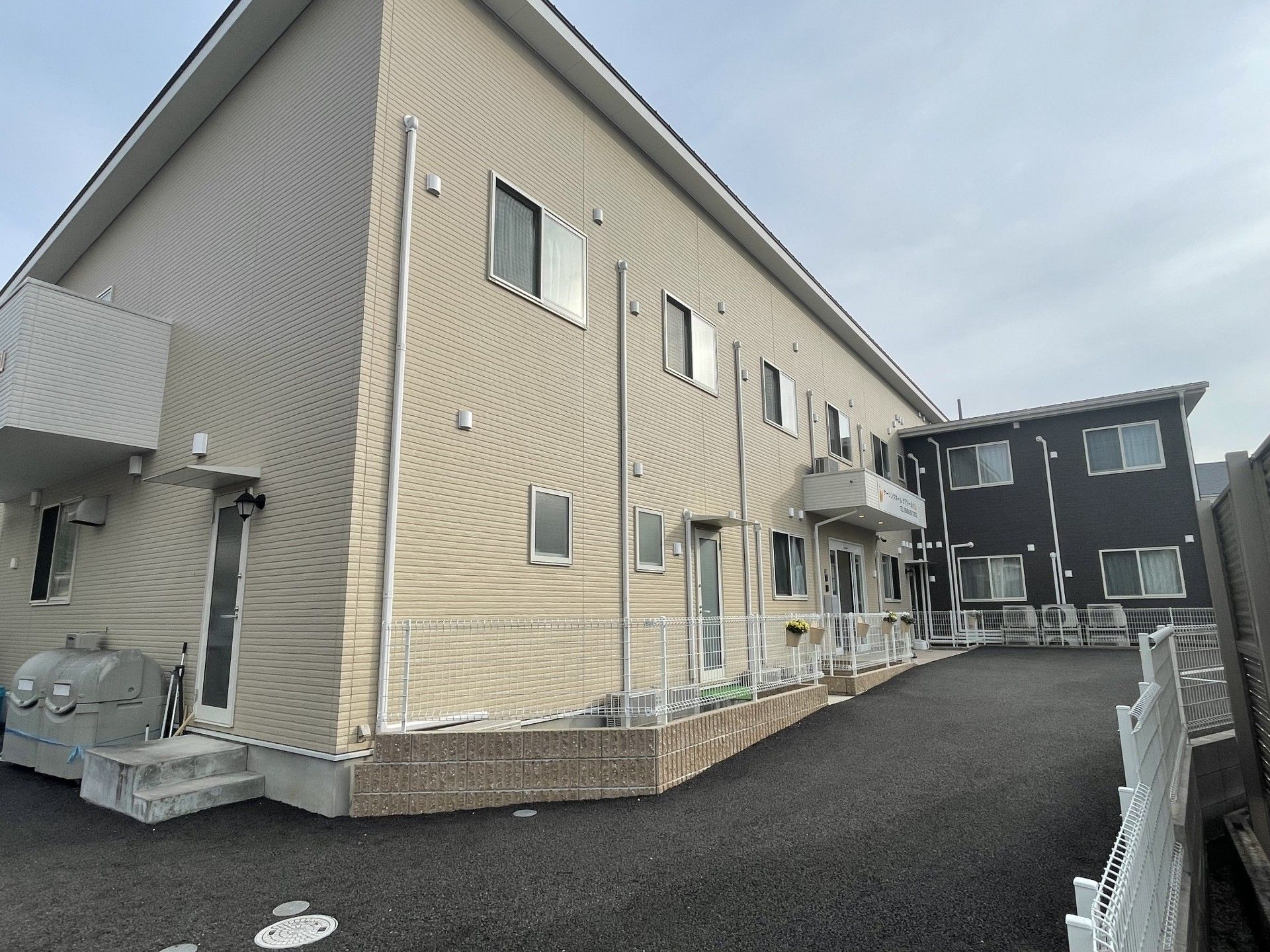 ブルーのユニフォームを着た男性スタッフと白い服を着た高齢女性が並んで体操をしている様子。二人とも同じポーズをしている。