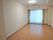 エアコンが付いたフローリングの部屋。大きな窓にはカーテンとレースカーテンが付き、家具などは置かれていない。天井には照明もある。