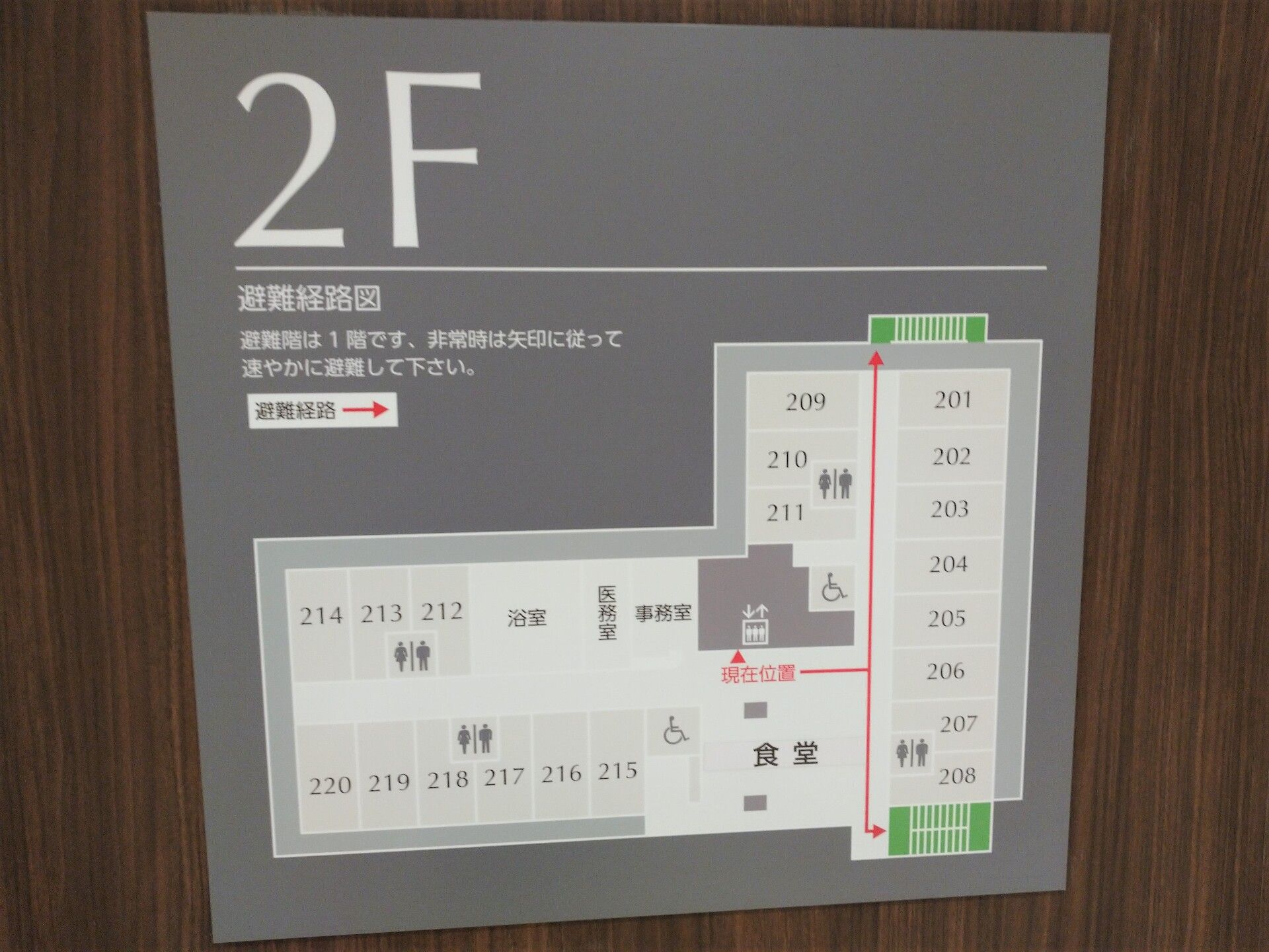 2階のフロアマップはシンプルなモノトーンでまとめられていて、非常階段がグリーン、現在地からそこまでの避難経路が赤い矢印で描かれている。