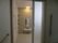 ドアが付いた浴室、少し薄暗くライトが付いている。中には何も置かれていないオープンタイプのラックがあり、シャワーも付いている。