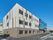 広い敷地内には緑が植えられ、3階建ての建物が建っている。1番下がダークブラウン、2階以上がベージュ。