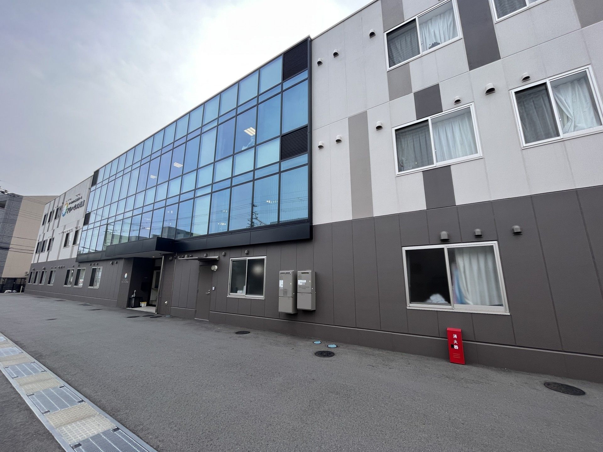 ベージュとダークブラウンの外観の3階建ての建物