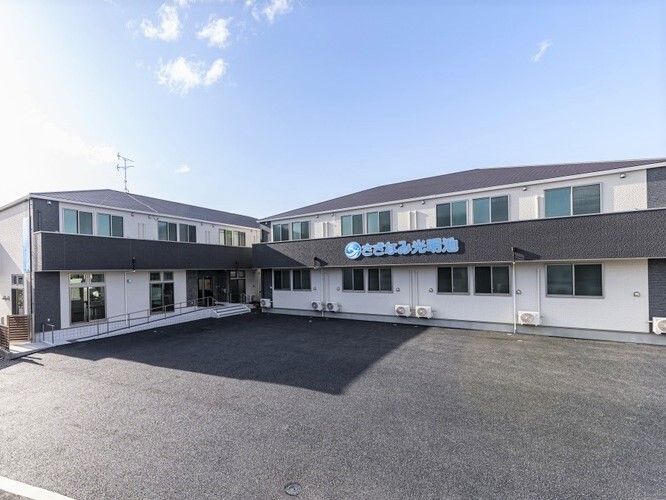 駐車場がある広い敷地とそこに建つさざなみ光明池の外観写真