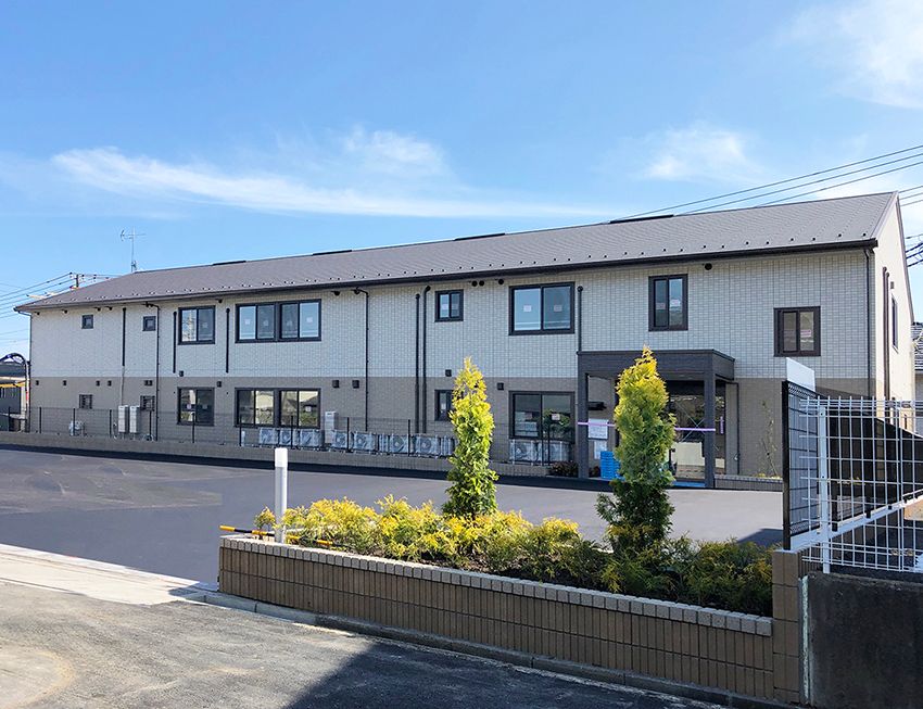 広い駐車場が付いた２階建ての建物は横に長く、玄関先には車寄せが付いている。