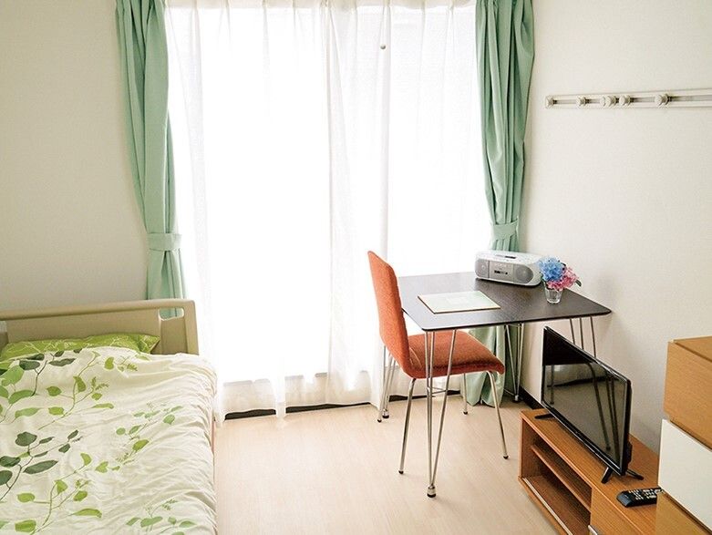 大きな窓が付いた部屋には寝具付きのベッドやデスクセット、テレビなどが置かれている。
