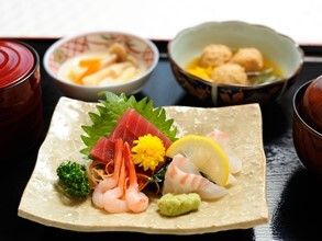 刺身の盛り合わせやつみれの煮物などが並べられた黒いトレー。汁椀にはふたがかぶせてある。