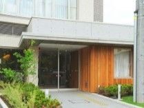 ワイドタイプの自動ドアが設置された玄関には屋根があり、点字ブロックが敷かれている。
