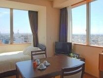 カーテンが付いた窓が２つある部屋には寝具付きのベッドやテーブルセットが置かれている。