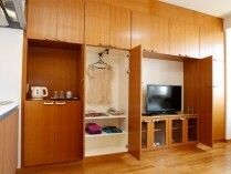 大きな壁面収納。扉を開けるとテレビが出てきて、横にはハンガーラックなどもある。