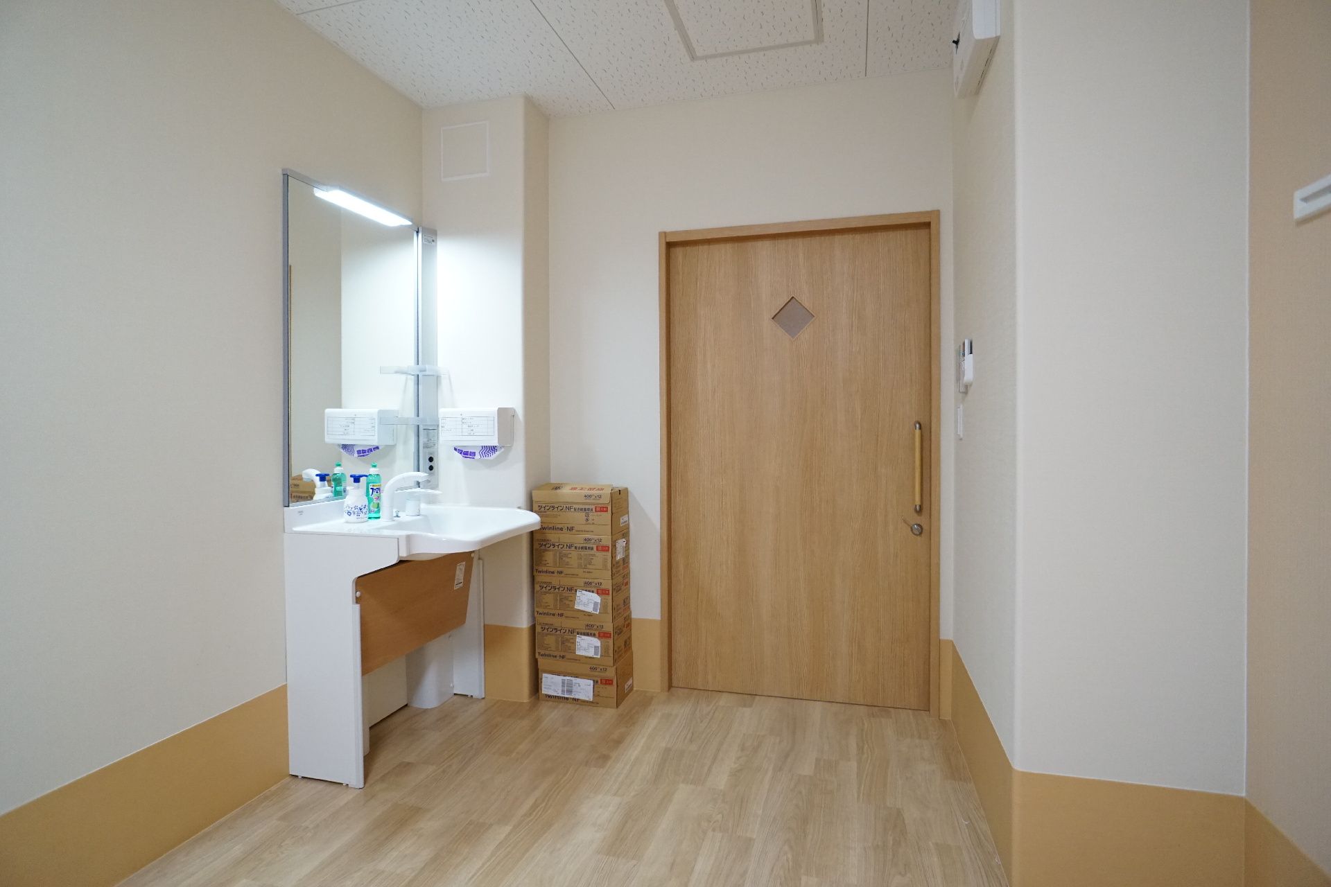壁沿いに洗面台が設置された茶色い扉の部屋