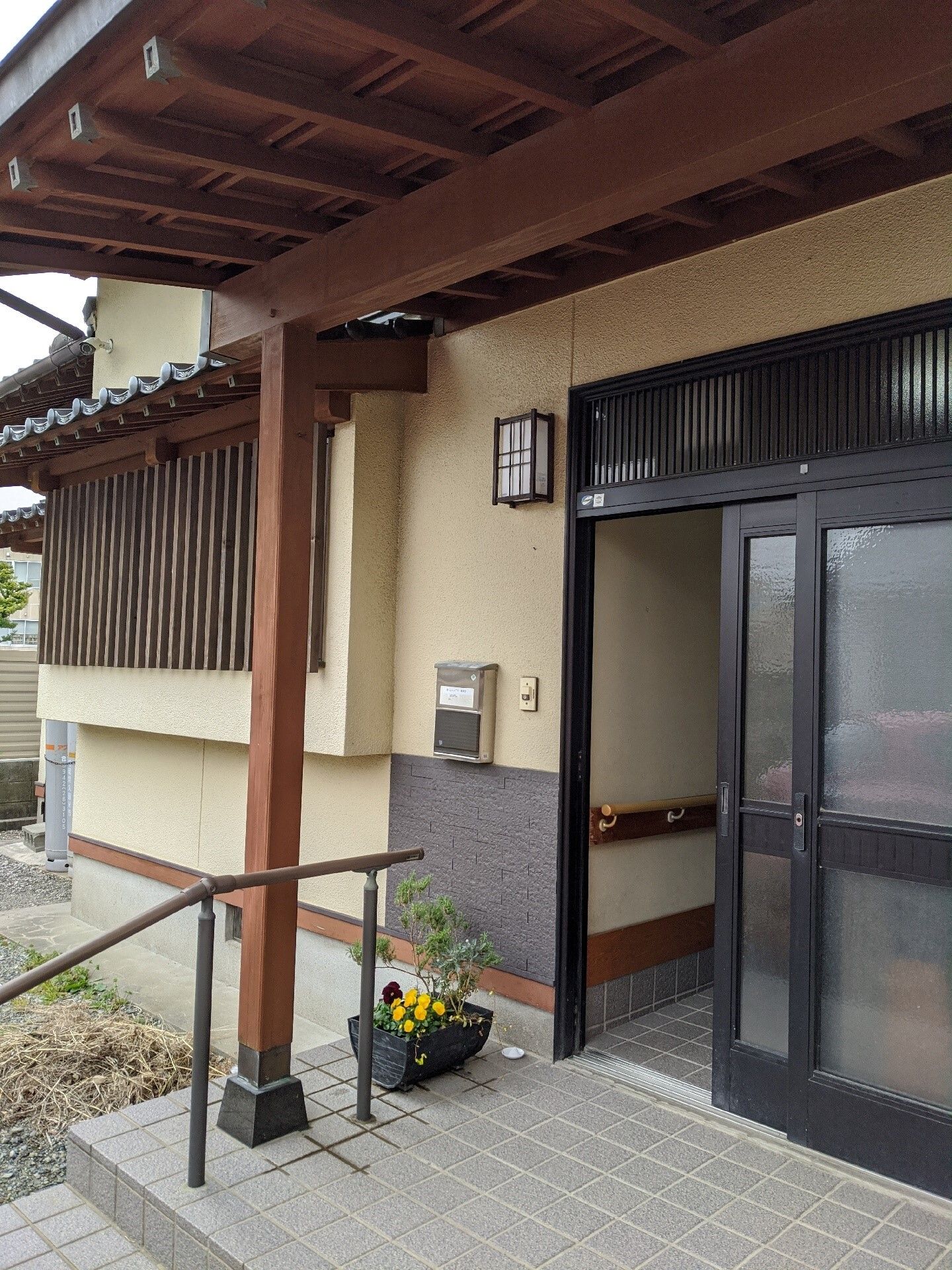 カメラに向かって笑顔を見せるスタッフと高齢者の女性。施設での何気ない一場面の様子