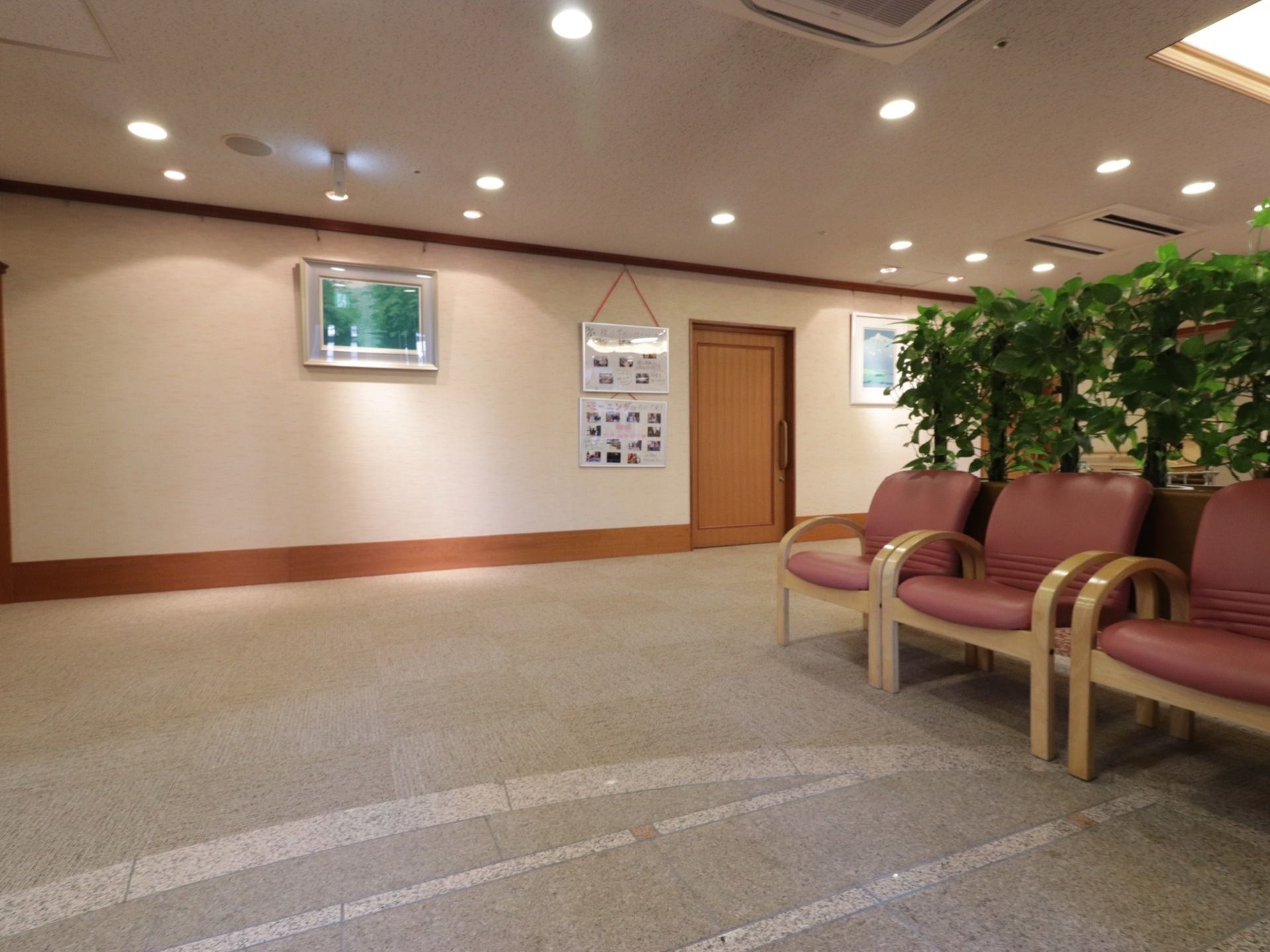 グリーンの前に、３台の椅子が並んで設置されている。奥の壁には、たくさんの写真が貼ってある白いパネルや絵が掛けてある。