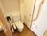温水洗浄機能が付いたトイレである。便器の左右に大きな手すりが設置されている。右側の壁には、緑色の呼出ボタンがある。