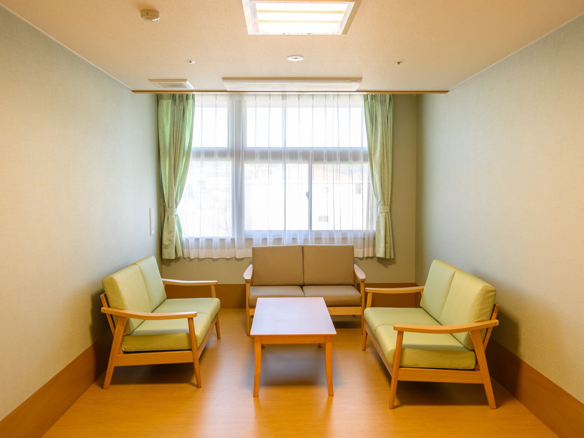 ピンクのエプロンを付けた若い女性スタッフが車いすの高齢女性と一緒に笑顔で話している。