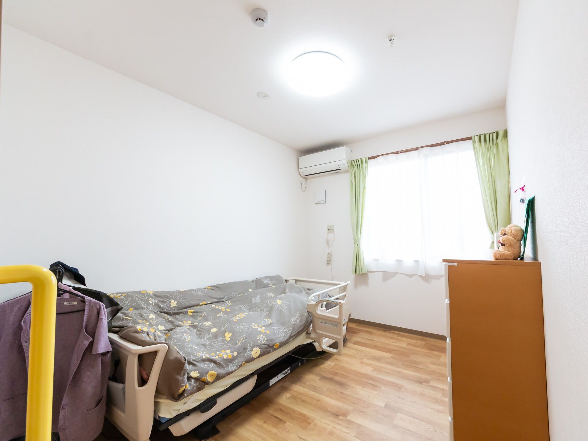 なにかを見て笑顔で手をたたいている高齢女性とスタッフの様子。施設での一場面の写真