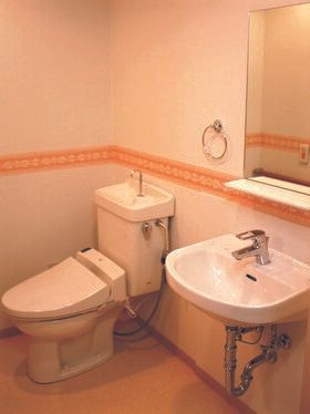 トイレと洗面所が同じ場所に設置されている。洗面所は車いす対応のデザインで、スペースも広い。壁には赤いレースのラインが貼られている。