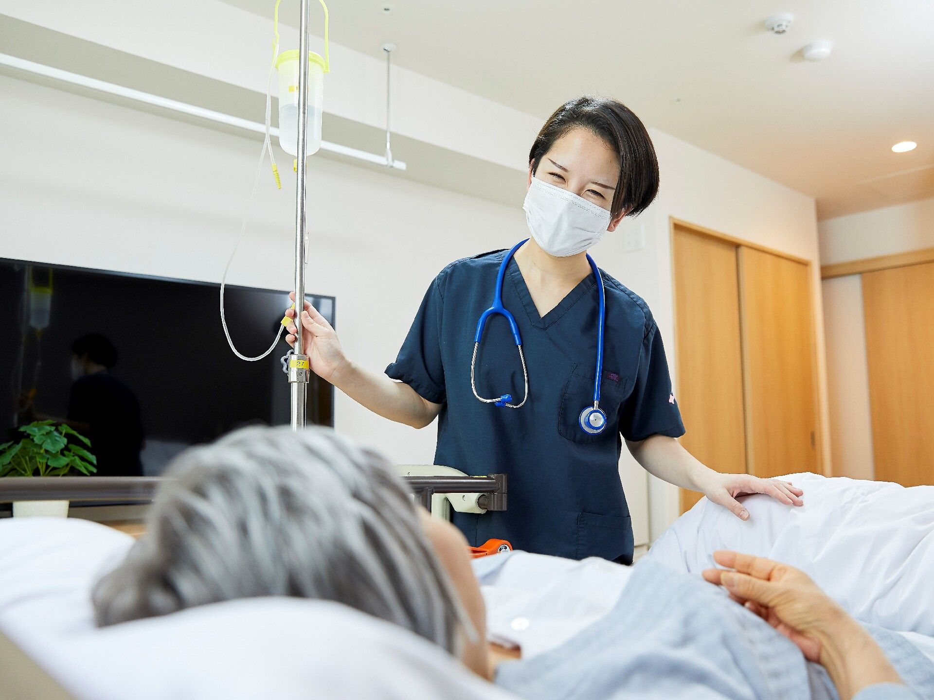 なにかに笑顔で手を振っている女性とその人の方を持ち同じ方向に笑顔を見せているスタッフ