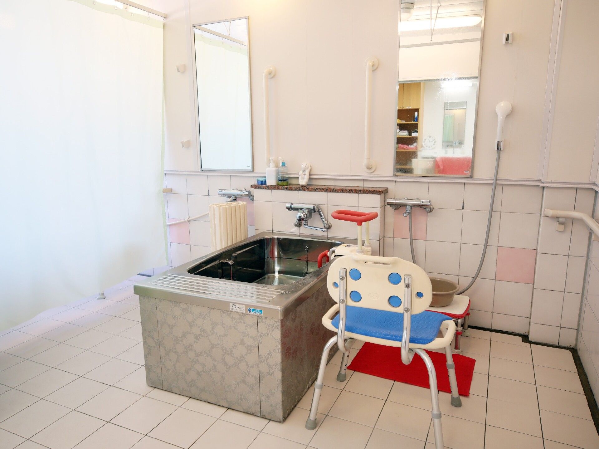 ステンレス製の一人用の浴槽が設置された浴室の洗い場は広く、シャワーチェアやシャワーも付いている。