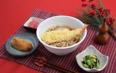 海老の天ぷらをトッピングしたそば、いなり寿司、野菜の和え物。