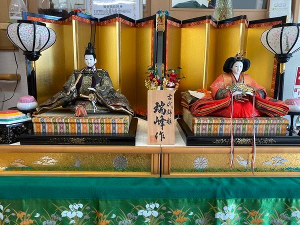 ハートの形に飾られている紙でできた花。その前にはひな人形が飾ら得ている。