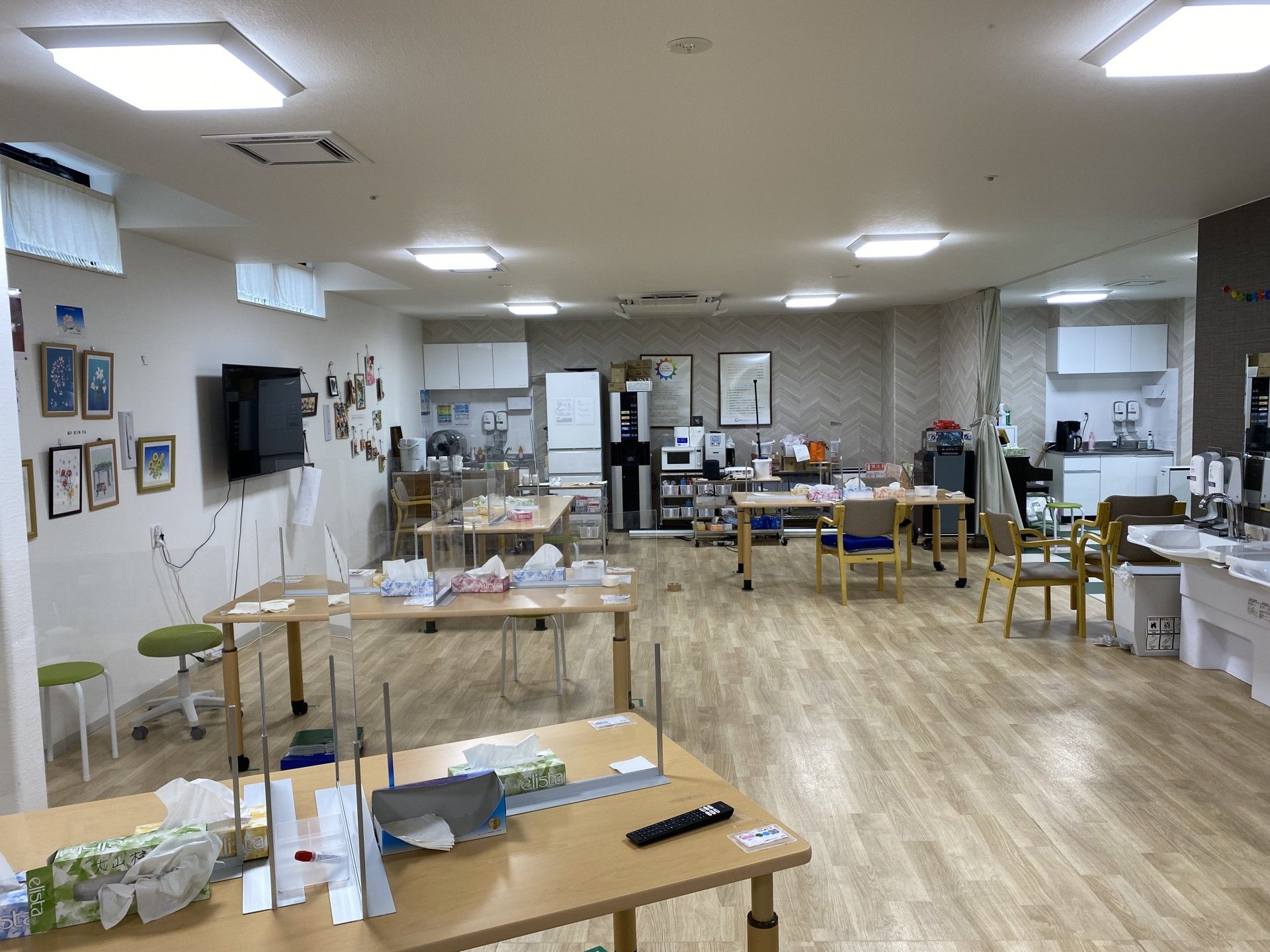 白いシャツを着た高齢男性の介助に笑顔で当たっているボーダー柄のエプロンを付けた女性スタッフ。