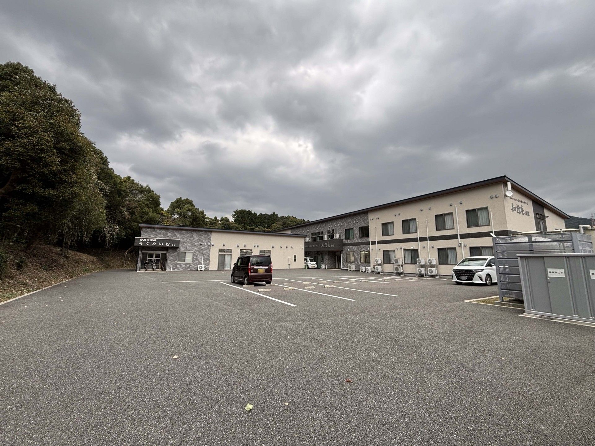 鏡を見ながら笑っている白髪の高齢女性とポロシャツを着た女性スタッフ。