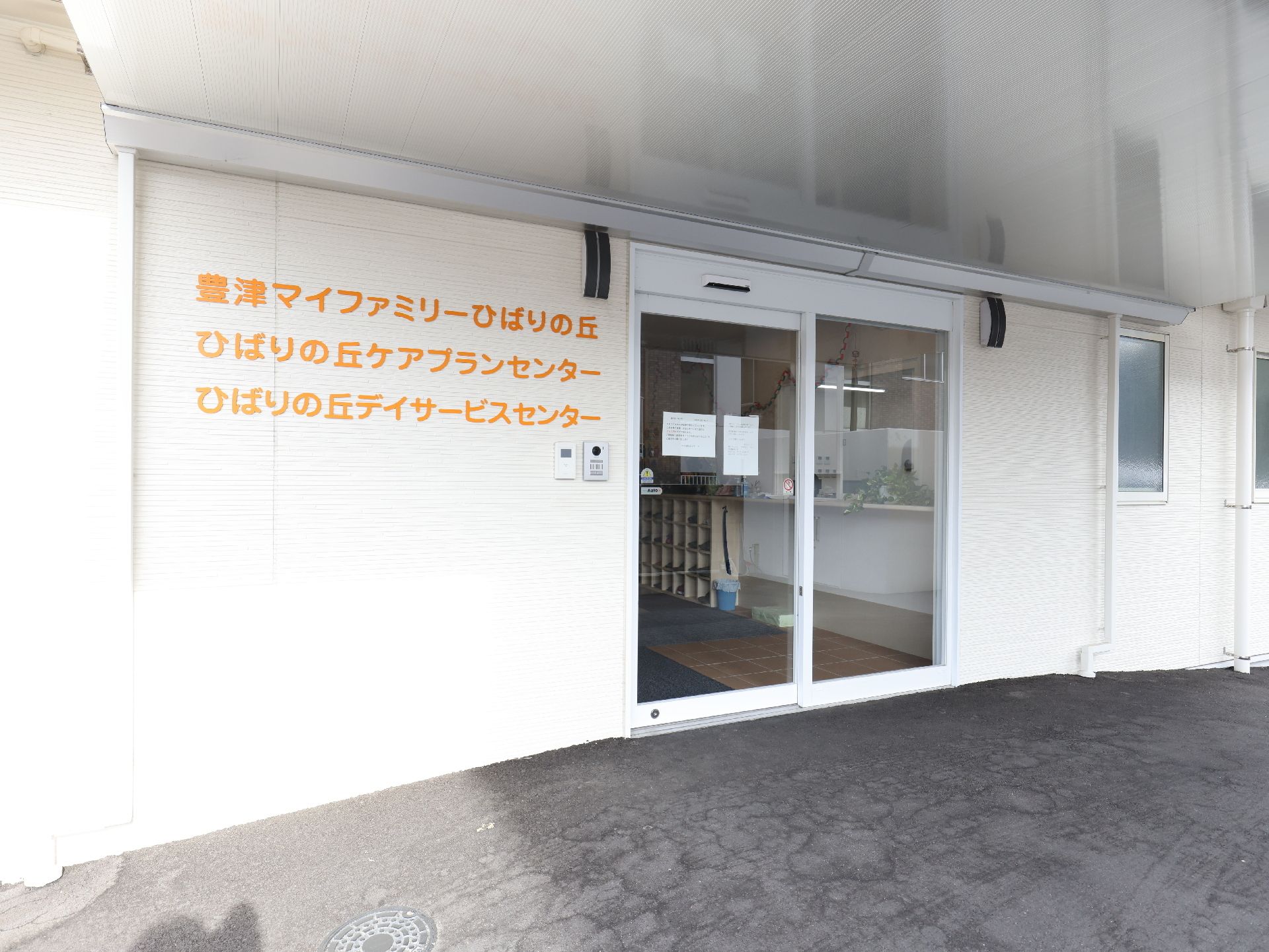 楽しそうに話している高齢女性たちと白衣を着た女性スタッフ。ベージュのソファを囲んでいる。