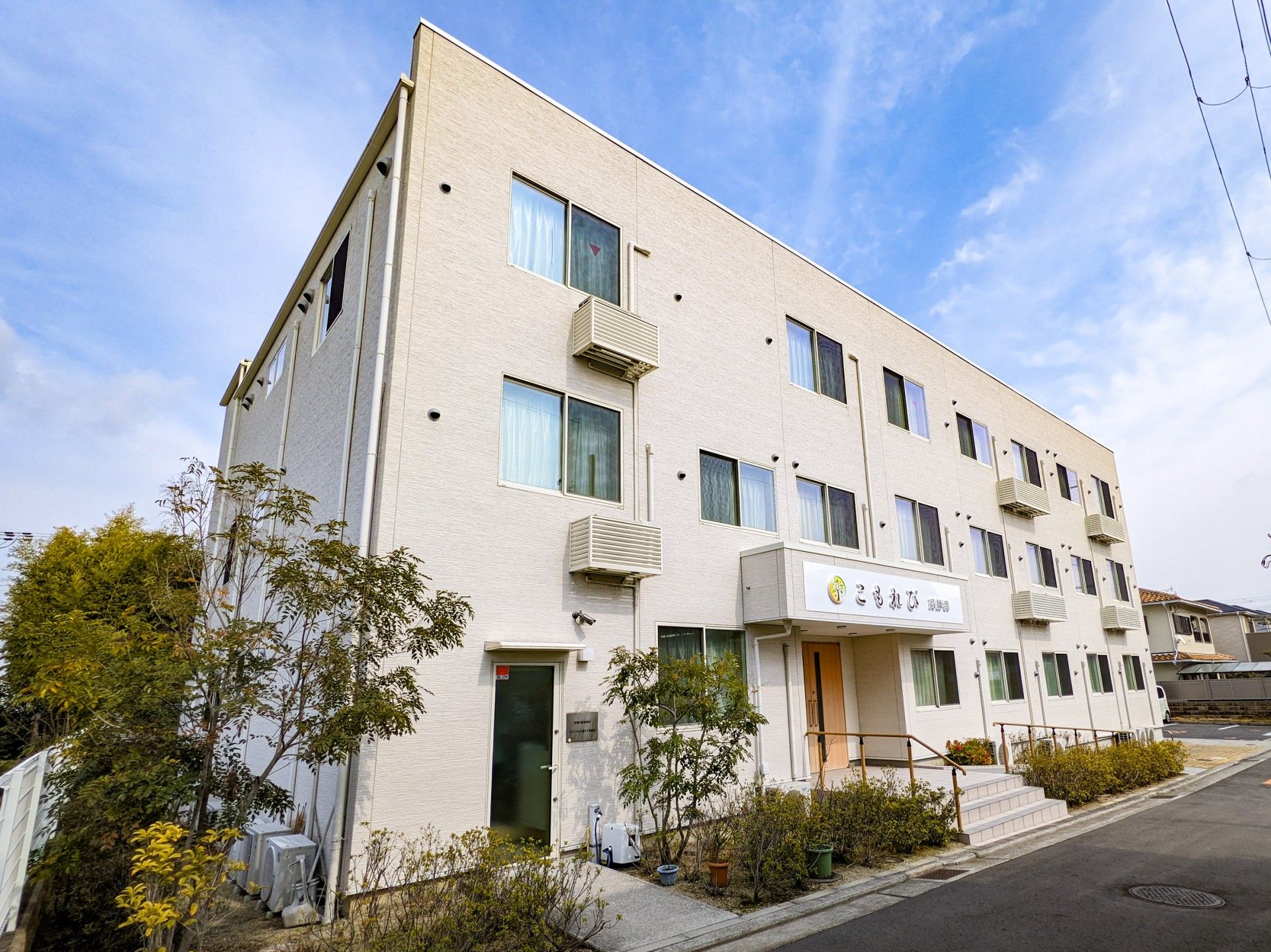 ベージュのソファを囲んで楽しそうに話している高齢女性たちと女性スタッフ。スタッフは両サイドの女性と手をつないでいる。