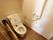 居室のトイレは個室になっており、便器の両脇に手すりが備えつけられている。左手の壁に操作パネルとペーパーホルダー、緊急呼出ボタンがある。
