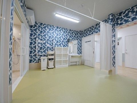 広い脱衣所はカーテンで仕切ることができ、浴室への出入り口には大きな引き戸が付いている。車いす対応の洗面所や棚、ゴミ箱などもある。
