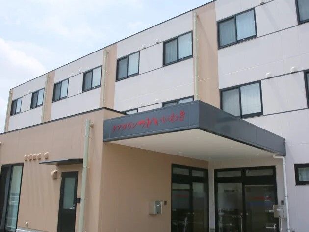 白とベージュの３階建ての建物の玄関には車寄せがあり、日当たりのいい場所に建っている。