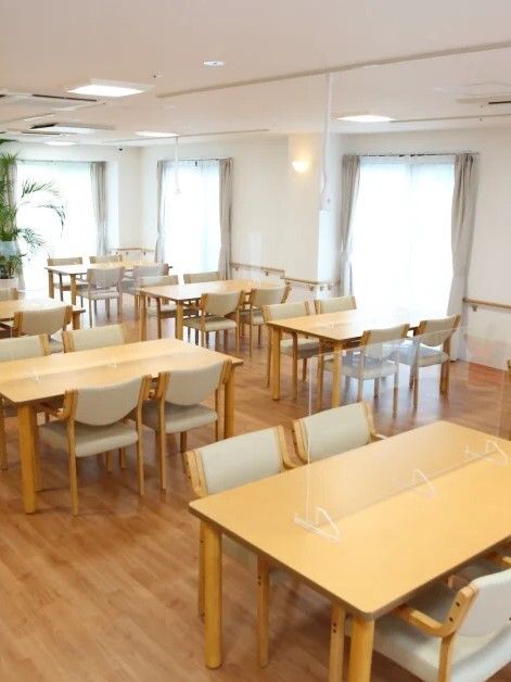 木製のダイニングテーブルは４人掛けで複数置かれている。観葉植物も飾られている。