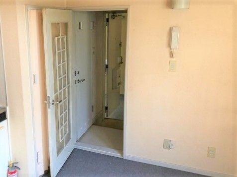 シンプルな部屋には押したり引いたりして開けるタイプの白いドアが付き、壁は薄いオレンジ色。白い受話器型のナースコールのようなものが付いている。
