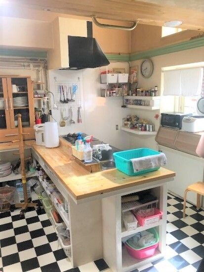 明るい雰囲気のキッチンは対面式で、フロアはモノクロのモザイク柄でおしゃれ。食器棚が壁際にあり、カウンターにはポットなどが置かれている。
