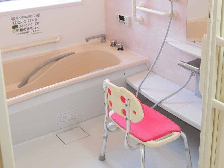 たくさんの手すりがついている浴室は一人用で、家庭サイズの浴槽が置かれ、シャワーの前にはシャワーチェアがあり、壁には鏡も付いている。