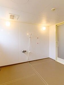 オレンジの呼び出しボタンが付いた浴室は広く、シャワーが壁についている。