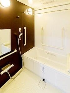 白と黒でまとめられた浴室には手すりがたくさんついている。一人用の浴槽が設置され、オレンジの呼び出しボタンが付いている。