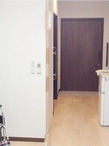 ダークブラウンのドアが付いた居室のドアからまっすぐな通路が続いていて、リビングスペースにはリモコンが設置されている。