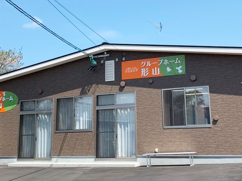 グループホーム形山の表示がある、茶色の外壁で三角屋根の平屋建てグループホーム