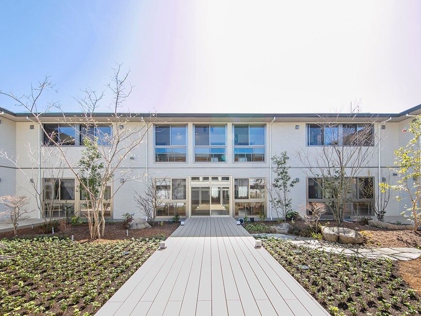 白を基調とした２階建ての建物は日当たりのいい場所に建っていて、敷地内には草木が植えられている。