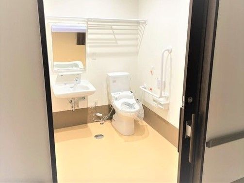 引き戸仕様のトイレを入り口から写した写真。広めのスペースで手すりと緊急コールがある