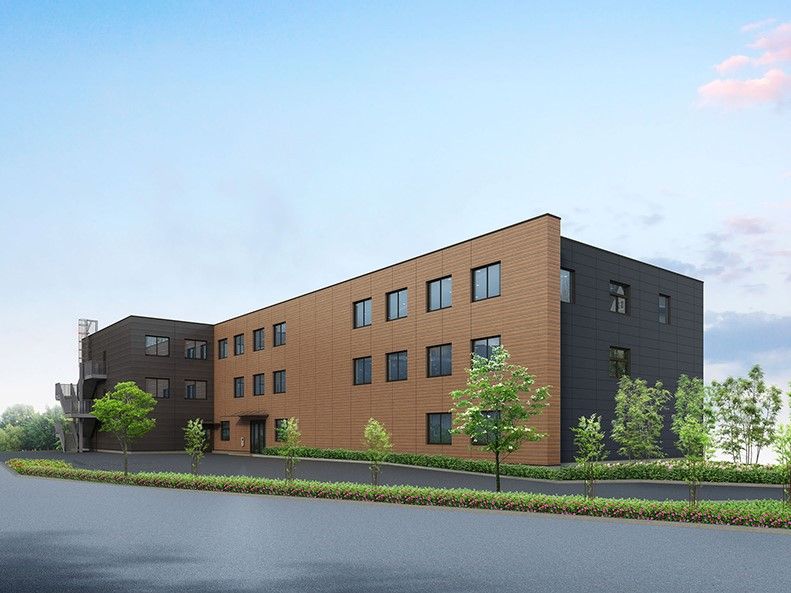 周囲を街路樹で囲まれた、茶色い外壁の3階建て建築物
