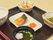 お吸い物がついたお膳で、花の形をしたかわいらしい麩が浮かんでいる。ごはん茶碗と、深鉢の配色がマッチしている。
