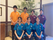 男女数名の施設の職員が、手の掌をカメラのほうに向かって見せたポーズをしている写真で、同じ色のユニフォームを着ている者がいる。