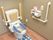 洋室トイレで、便座ーシートとマットが敷いてある。手すりが両サイドにあり、立ち居が楽である。緊急時のブザーが設置してある。