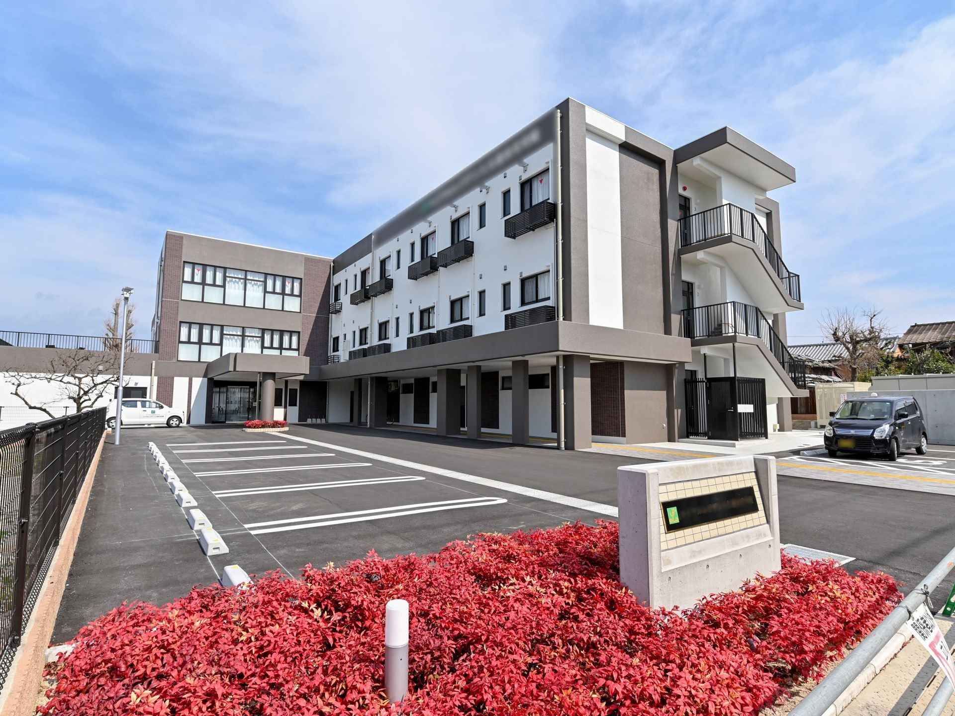ブラウンと白を基調とした３階建ての大きな建物である。敷地内には駐車場も設けられており、たくさんの車を停められる。