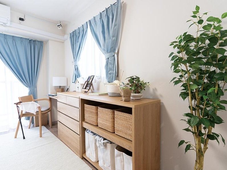 観葉植物が飾られている部屋には大きな窓があり、木製のタンスや棚、テーブルセットも設置されている。