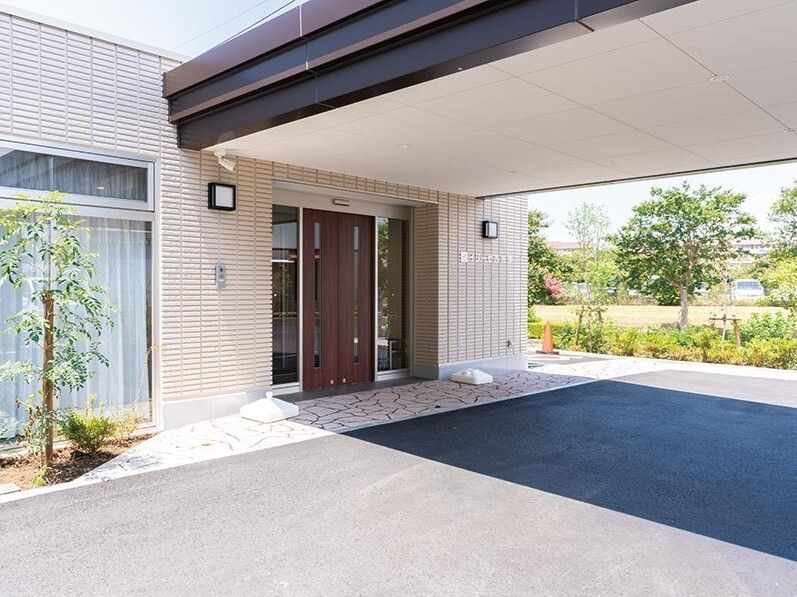 草木がたくさん植えられたエントランス周辺。玄関には大きな車寄せが付き、影ができている。